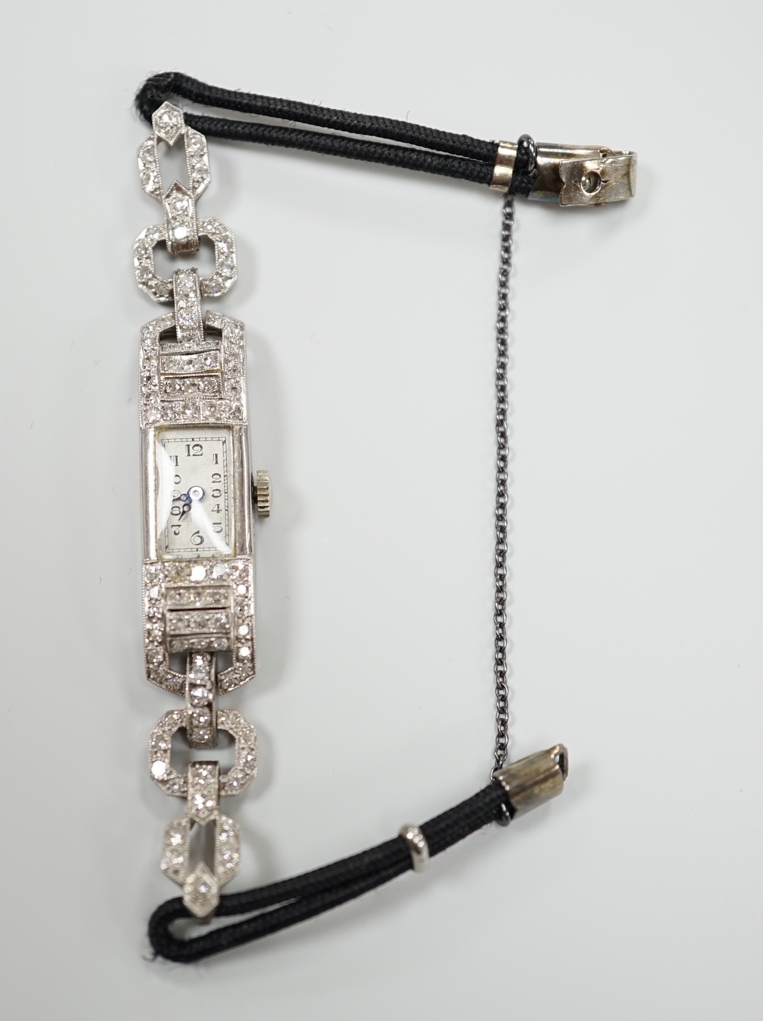A lady's 1930's/2940's white metal (engraved All Platine) and diamond set manual wind cocktail watch, on a twin fabric strap.